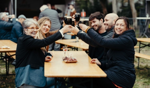 Menschen am Tisch sehen glücklich aus mit Getränk in der Hand.